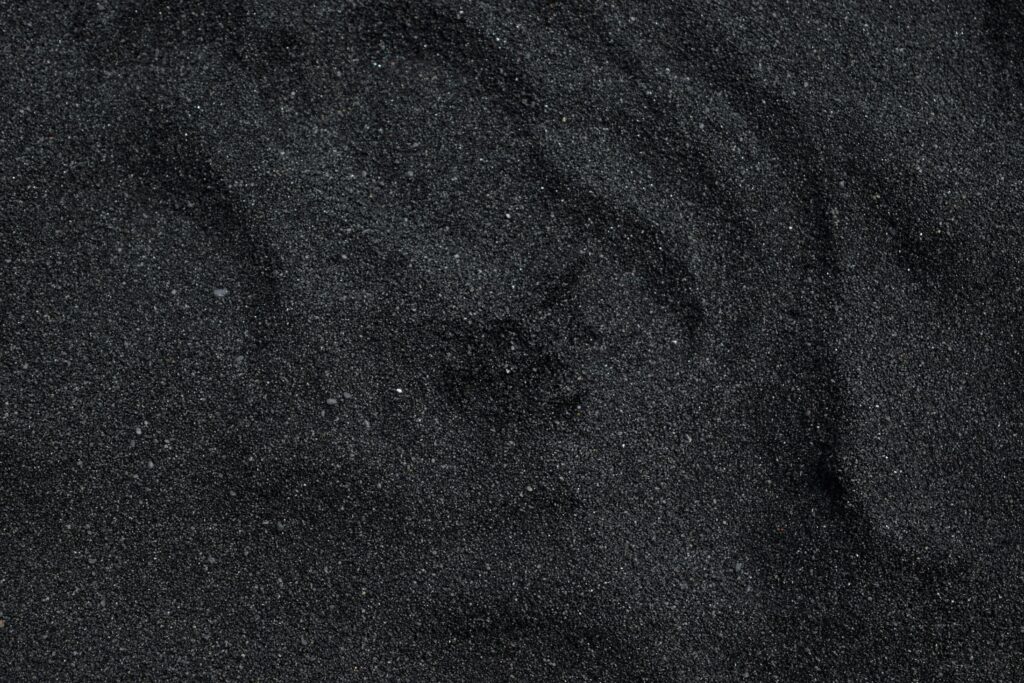 Close-up of black sand texture from Waimea Beach in Hawaii. Ideal for backgrounds.